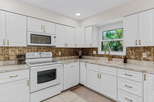 a kitchen with cabinets stainless steel appliances a sink and a window