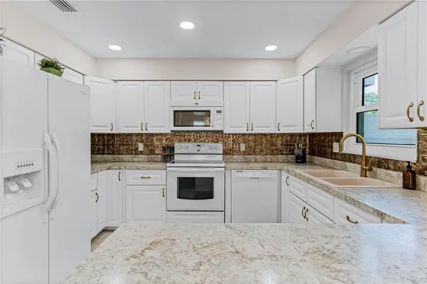 a kitchen with cabinets appliances a sink and a counter top space