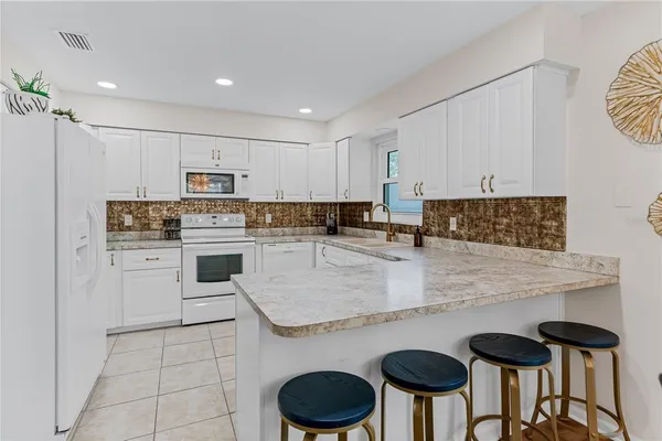 a kitchen with stainless steel appliances granite countertop a table chairs sink and cabinets