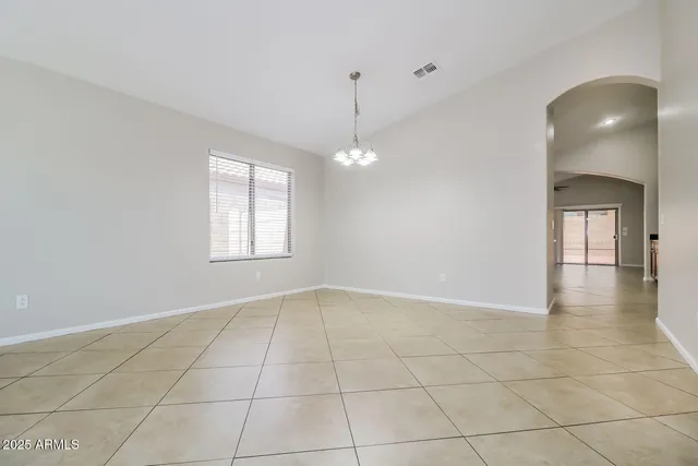 a view of an empty room with window and chandelier fan