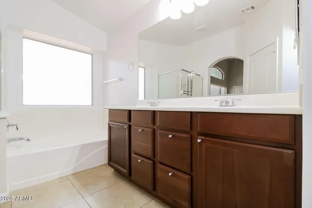 a bathroom with a double vanity sink a mirror and bathtub