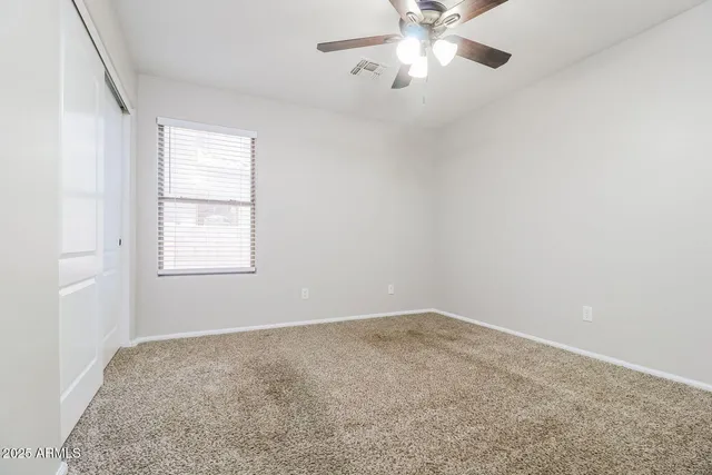 an empty room with a window and a fan