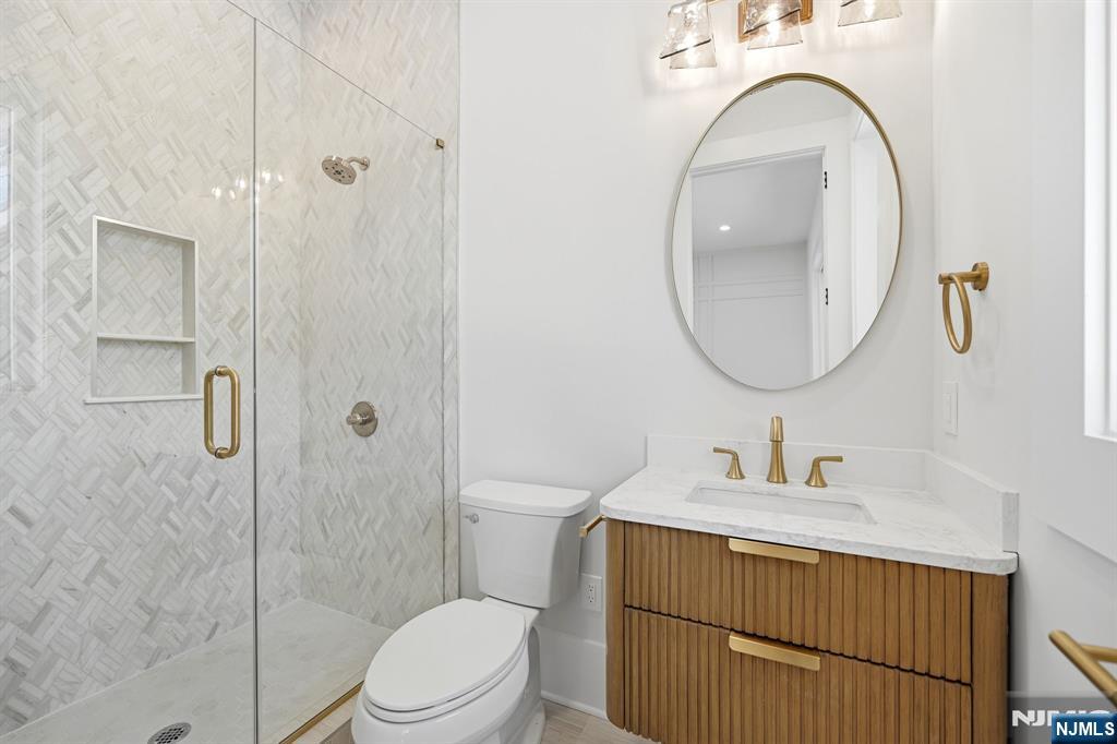 8 Montgomery Road Livingston, NJ 07039 - Photo 29 of 38 a bathroom with a sink a mirror a toilet and shower