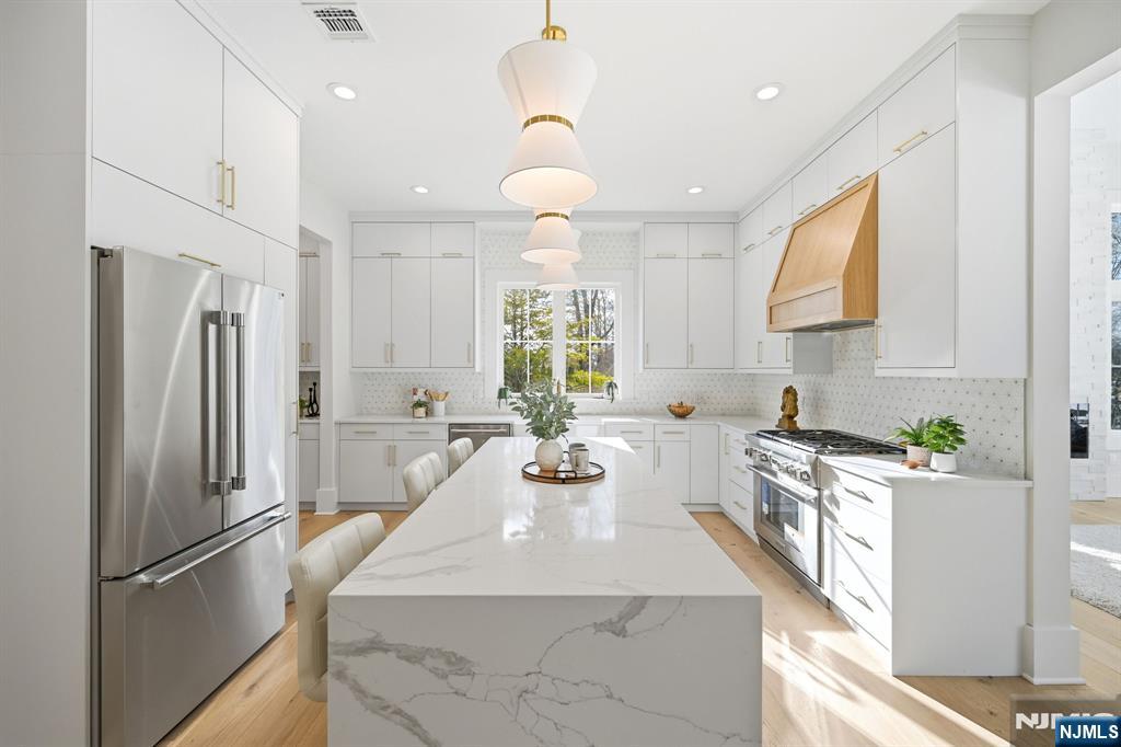 8 Montgomery Road Livingston, NJ 07039 - Photo 9 of 38 a kitchen with stainless steel appliances a refrigerator a sink dishwasher a oven with white cabinets and wooden floor