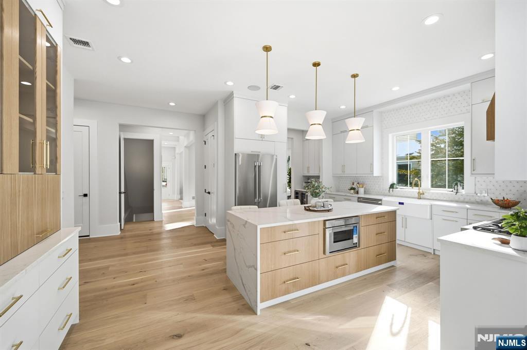 8 Montgomery Road Livingston, NJ 07039 - Photo 10 of 38 a large kitchen with kitchen island a stove a sink dishwasher and a fireplace with wooden floor