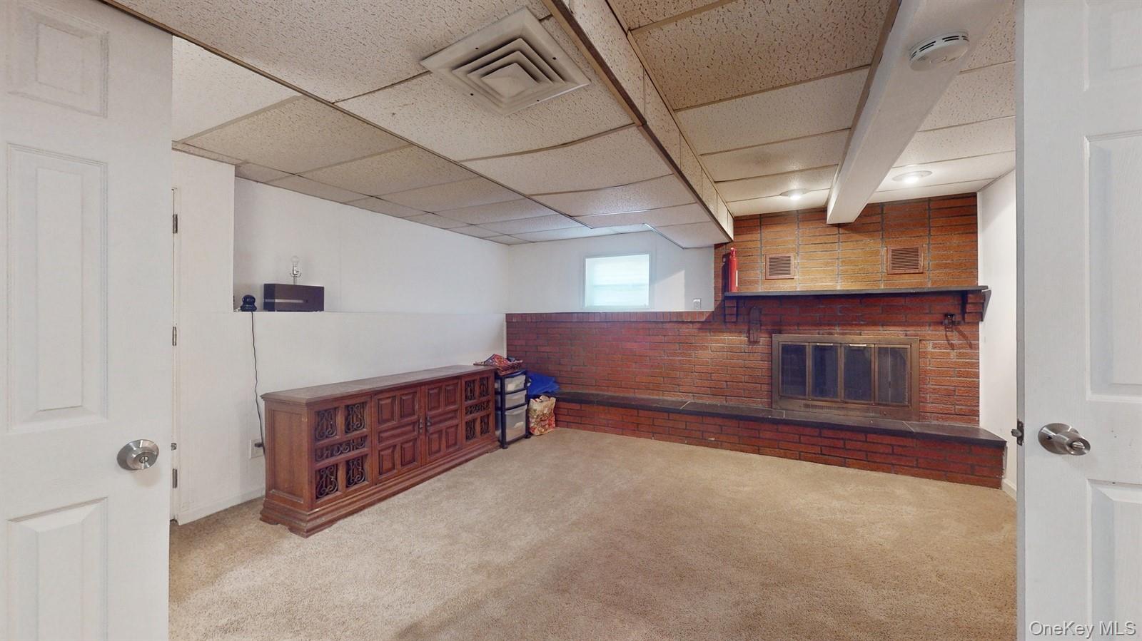 10 Rumbrook Road Elmsford, NY 10523 - Photo 15 of 25 Family rm featuring a paneled ceiling, light carpet, a fireplace, and brick wall. Walk out.