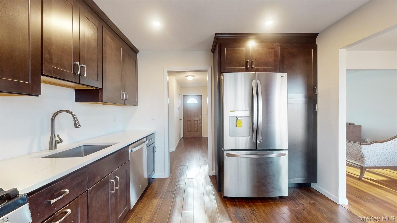 10 Rumbrook Road Elmsford, NY 10523 - Photo 8 of 25 Kitchen featuring sink, light stone countertops, dark hardwood / wood-style flooring, dark brown cabinetry, and stainless steel appliances
