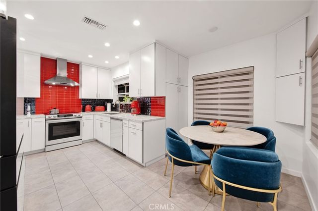 a kitchen with stainless steel appliances kitchen island granite countertop a table chairs and a refrigerator