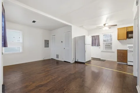 a view of an empty room with window and wooden floor