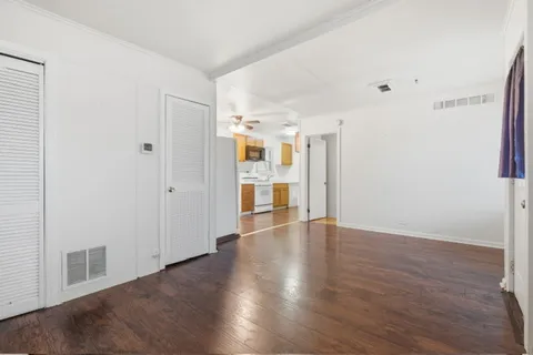 a view of an empty room with wooden floor and a window
