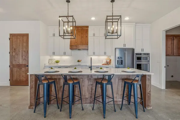 a kitchen with stainless steel appliances a table chairs refrigerator and sink