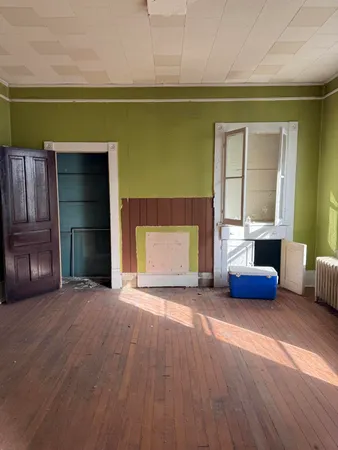 a view of empty room with a fireplace and wooden floor