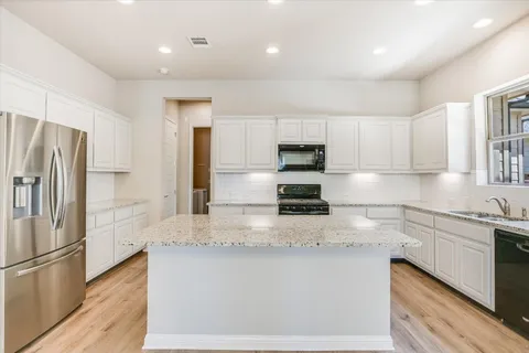 a kitchen with kitchen island granite countertop white cabinets and refrigerator