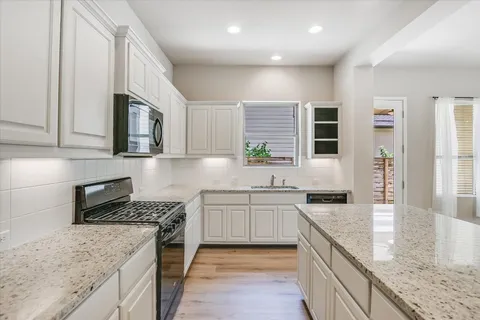 a kitchen with stainless steel appliances granite countertop a stove a sink and a microwave