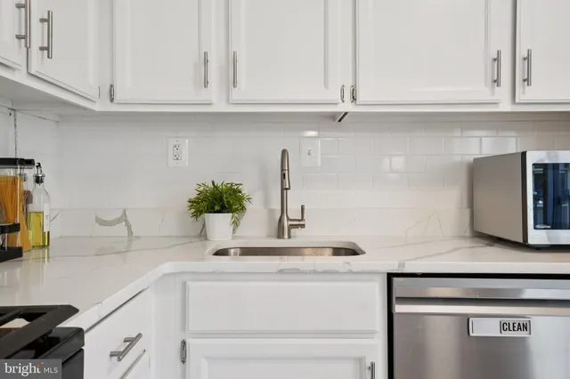 a kitchen with granite countertop white cabinets and a stainless steel appliances