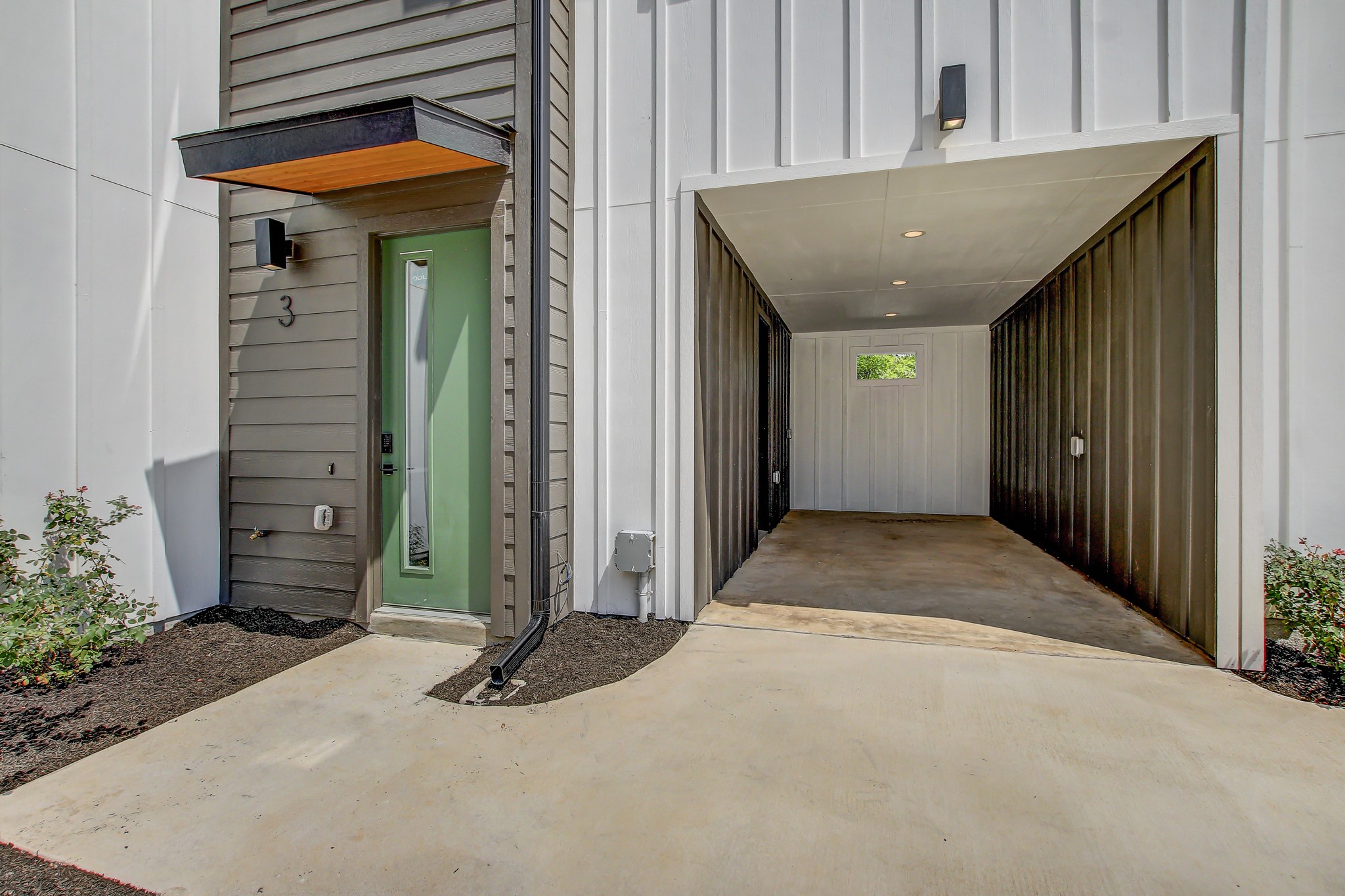 4127 East 12th Street, Unit 3 Austin, TX 78721 - Photo 24 of 29 Doorway to property featuring board and batten siding, driveway, and a carport