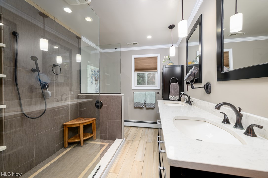5304 Sibila Road Northwest Canton, OH 44718 - Photo 23 of 29 Bathroom featuring double sink vanity, a baseboard heating unit, crown molding, and tiled shower
