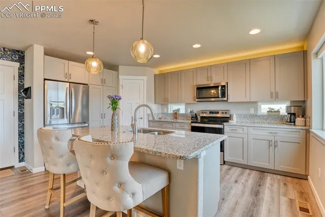 a kitchen with kitchen island granite countertop a sink a center island a stove cabinets and a dining table