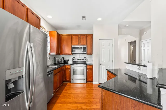 a kitchen with stainless steel appliances granite countertop a refrigerator a stove and a sink