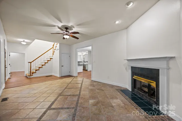 an empty room with wooden floor a ceiling fan and windows