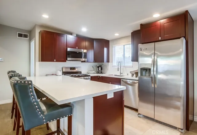 a kitchen with stainless steel appliances granite countertop a refrigerator a stove a sink a dining table and chairs