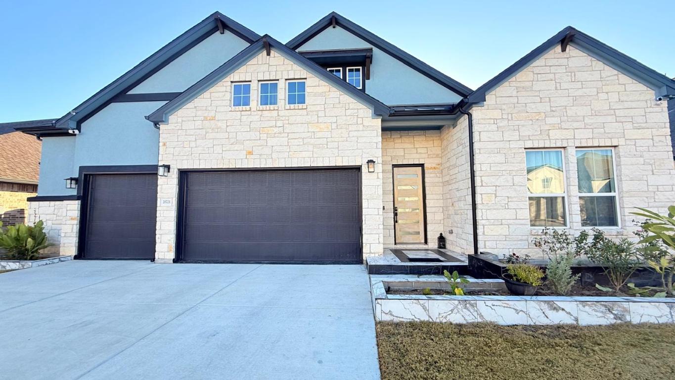 20721 Dustin Lane Pflugerville, TX 78660 - Photo 2 of 27 View of front facade featuring stone siding, driveway, and a garage