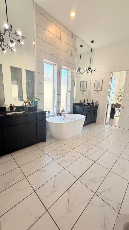 20721 Dustin Lane Pflugerville, TX 78660 - Photo 25 of 27 Full bathroom with a chandelier, light marble finish floors, a freestanding tub, two vanities, and recessed lighting