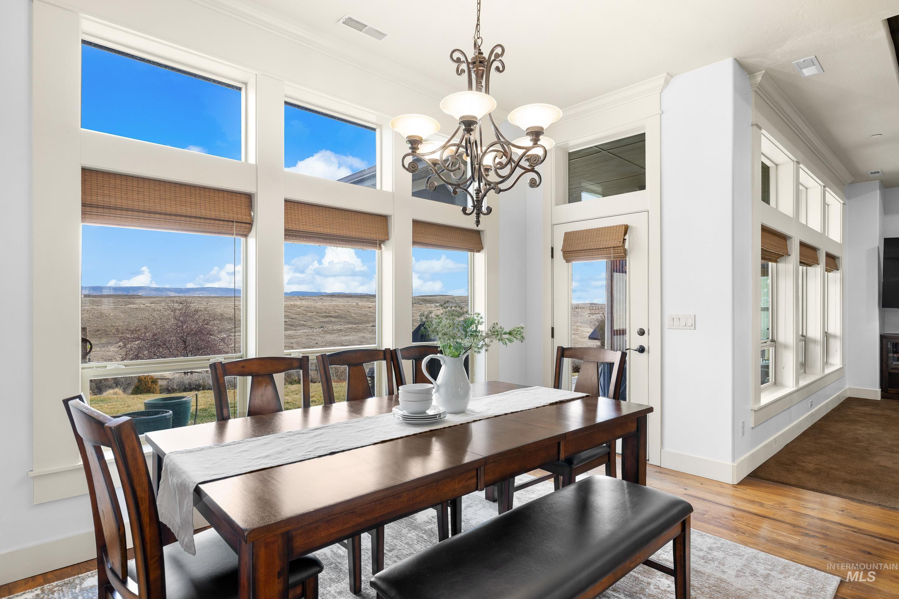 7521 North Grand Ridge Lane Eagle, ID 83616 - Photo 25 of 50 Dining area featuring light wood-style flooring, a chandelier, ornamental molding, and a high ceiling