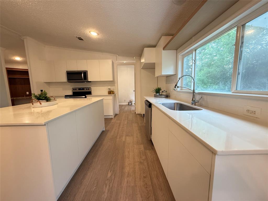 2002 County Road 906 Princeton, TX 75407 - Photo 10 of 31 a kitchen with a sink a counter top space a large window and stainless steel appliances