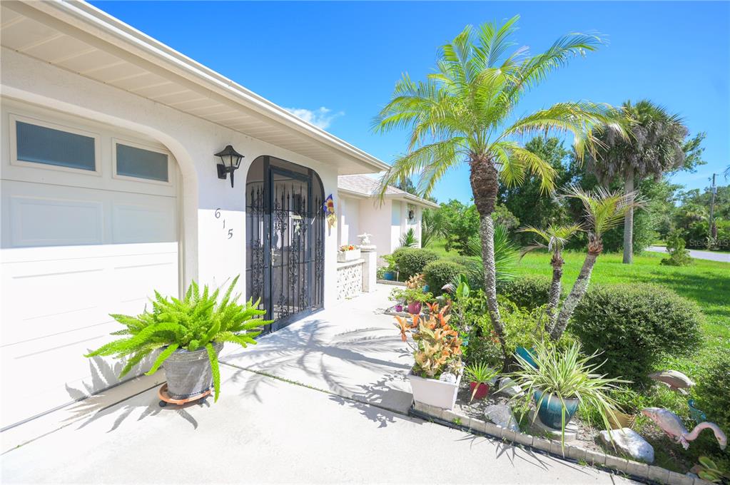 615 Toledo Road North Port, FL 34287 - Photo 3 of 16 a vase of flowers sitting on a yard with potted plants