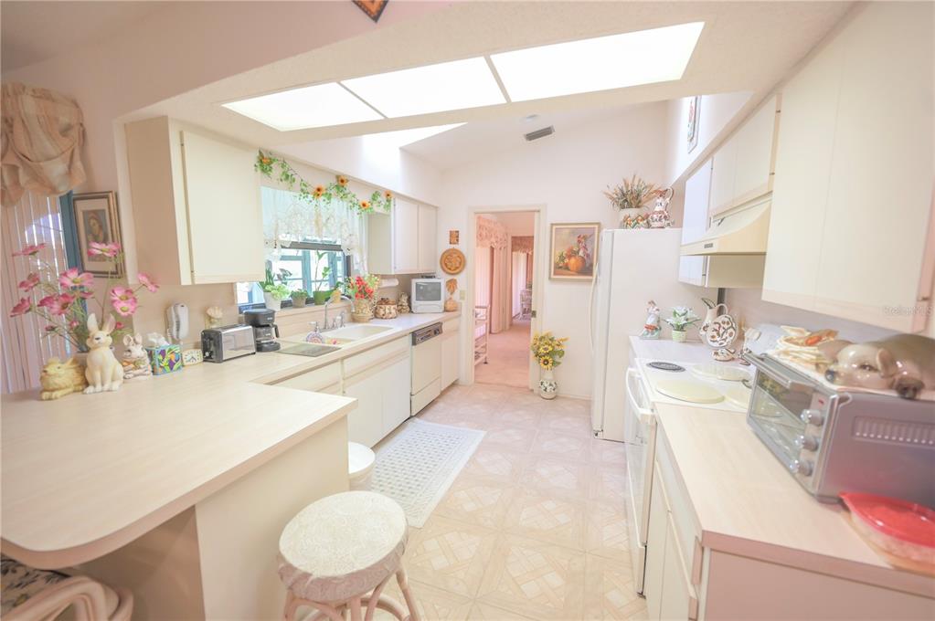 615 Toledo Road North Port, FL 34287 - Photo 7 of 16 a large white kitchen with a stove a sink dishwasher a dining table and chairs with wooden floor