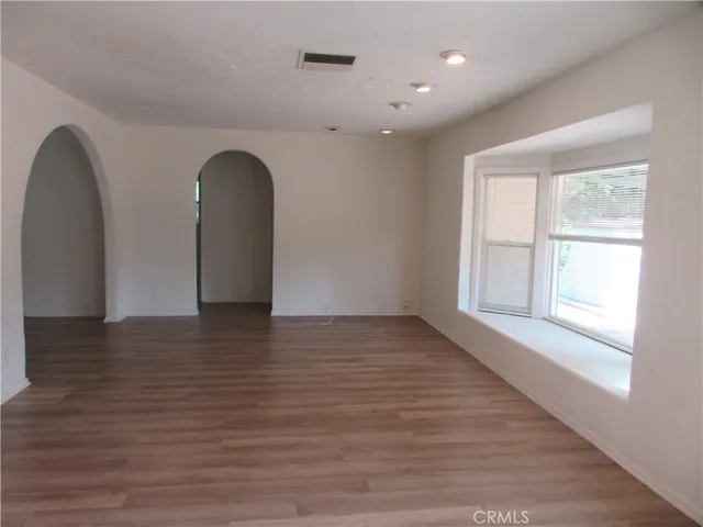 a view of empty room with window and wooden floor