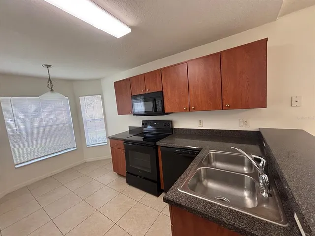 a kitchen with granite countertop a sink dishwasher stove and microwave oven