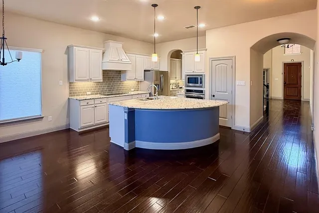 a kitchen with stainless steel appliances granite countertop a sink stove and wooden floor