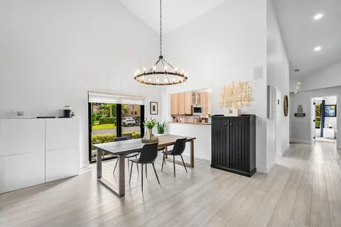 a dining room with wooden floor a chandelier a wooden table and chairs