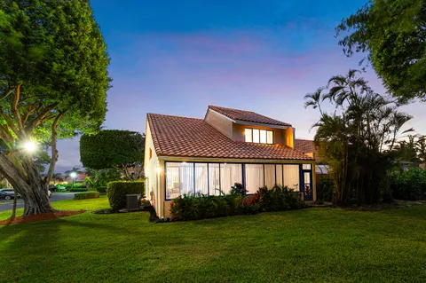 a view of a house with a big yard and palm trees