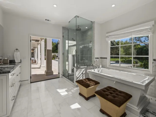 a large white bathroom with a double vanity sink a mirror and a shower