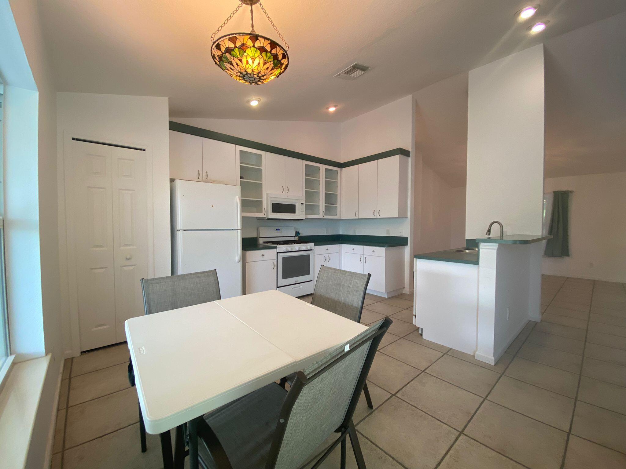 5425 Koblegard Road Fort Pierce, FL 34951 - Photo 11 of 33 a kitchen with a table chairs and a refrigerator