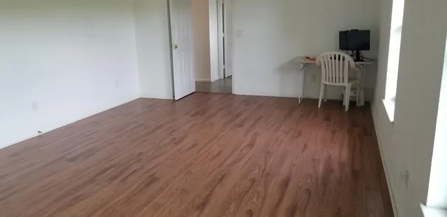 an empty room with wooden floor and windows