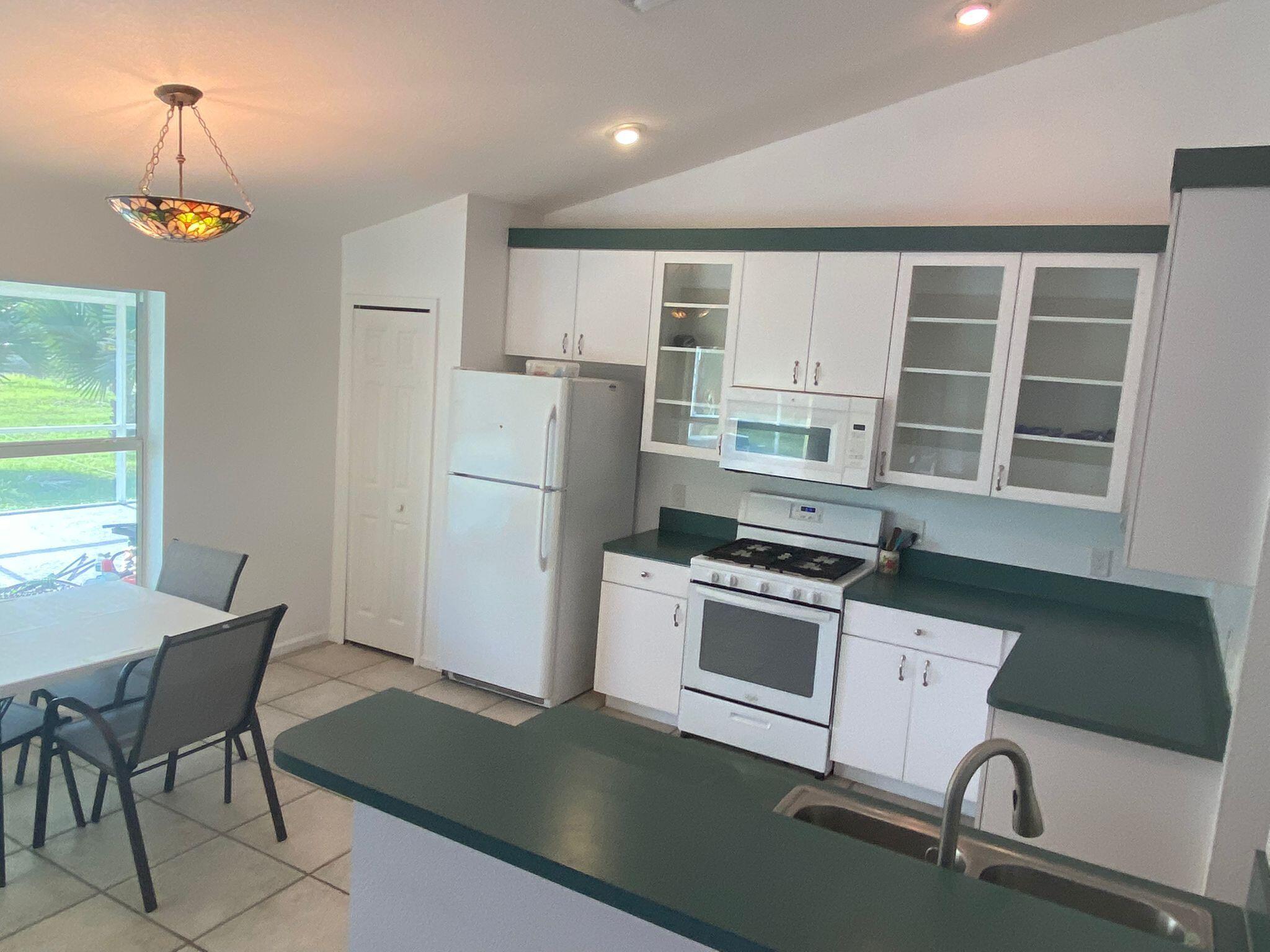 5425 Koblegard Road Fort Pierce, FL 34951 - Photo 8 of 33 a kitchen with kitchen island a stove a refrigerator and a dining table with wooden floor
