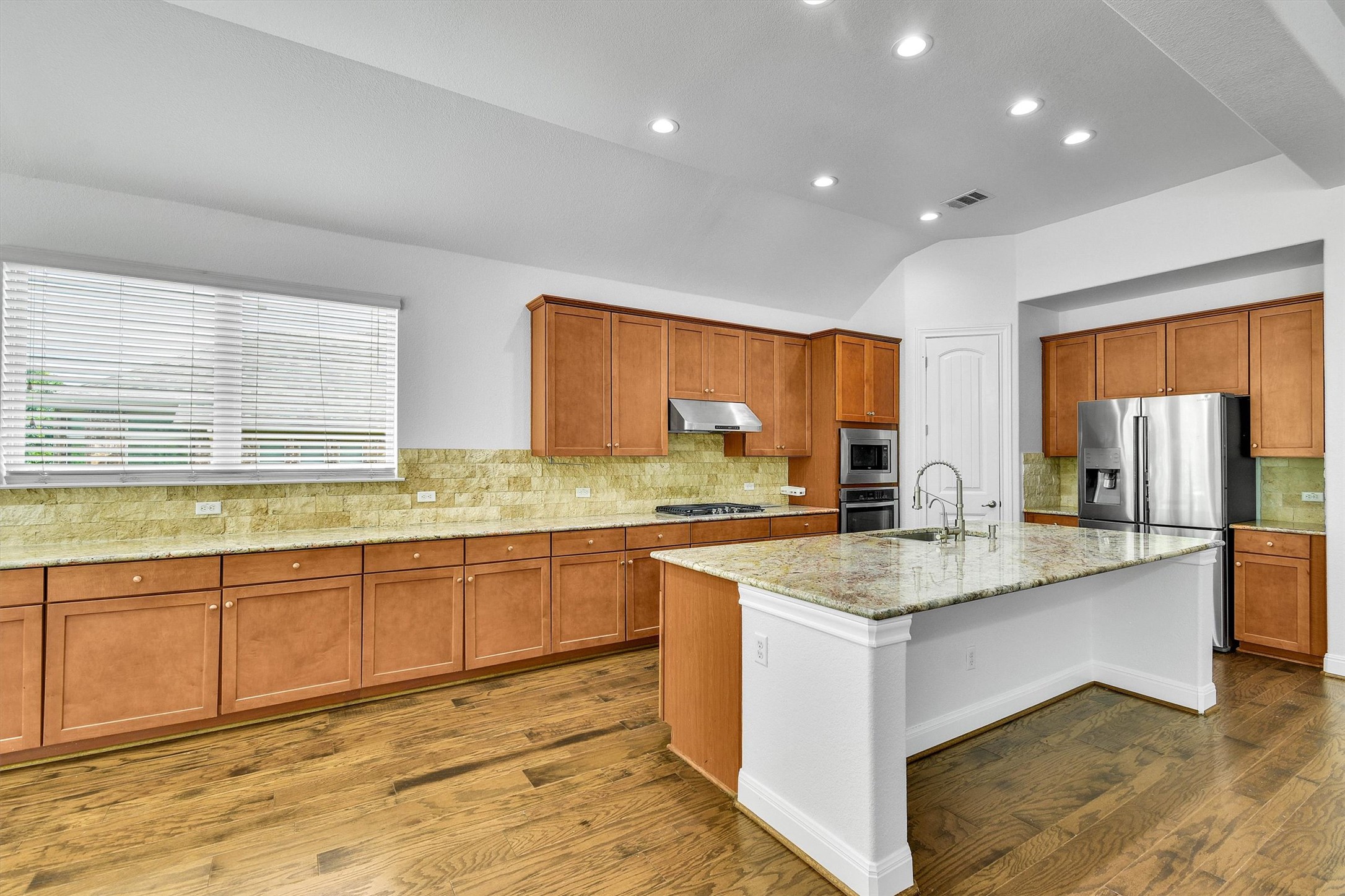 2325 Blended Tree Ranch Drive Leander, TX 78641 - Photo 12 of 35 A grand central island anchors this spacious kitchen, boasting rich wood cabinetry and ample counter space.