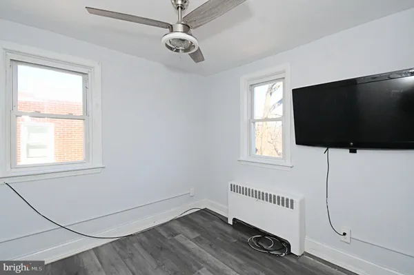 an empty room with wooden floor fan and windows