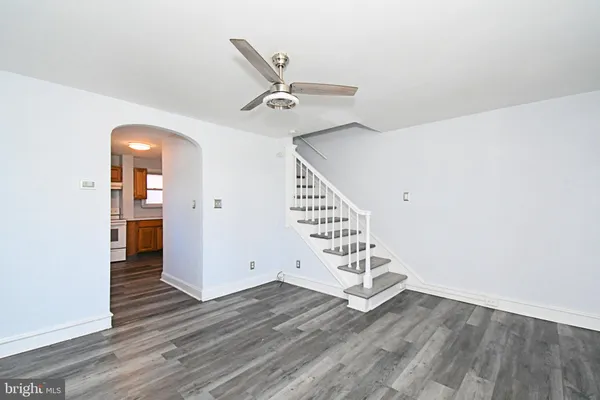 an empty room with wooden floor white walls and windows