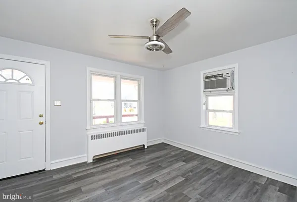 an empty room with wooden floor a ceiling fan and windows