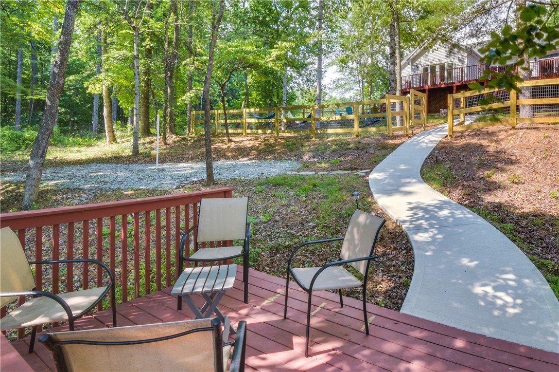 206 Petty Road Seneca, SC 29672 - Photo 7 of 48 An inviting deck extends to a winding path, leading toward the home nestled among vibrant trees.