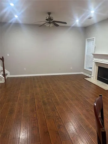 an empty room with wooden floor fireplace and windows