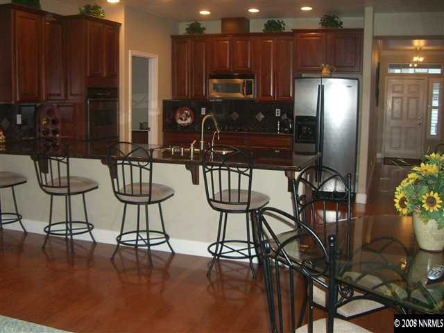 10823 Rushing Flume Drive Reno, NV 89521 - Photo 3 of 9 a kitchen with stainless steel appliances a dining table chairs and a refrigerator