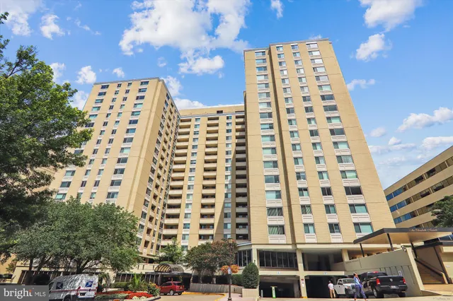 a living room with couches and kitchen view with wooden floor