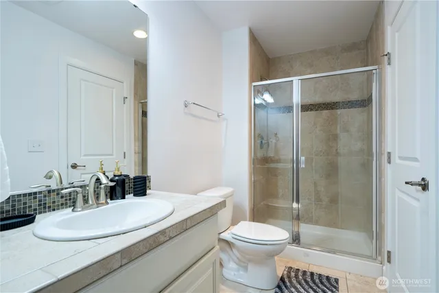 a bathroom with a granite countertop sink toilet a mirror and shower