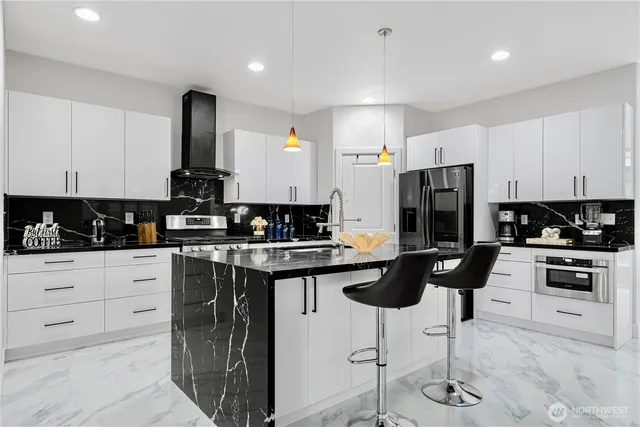 a kitchen with stainless steel appliances kitchen island granite countertop a stove a refrigerator and white cabinets